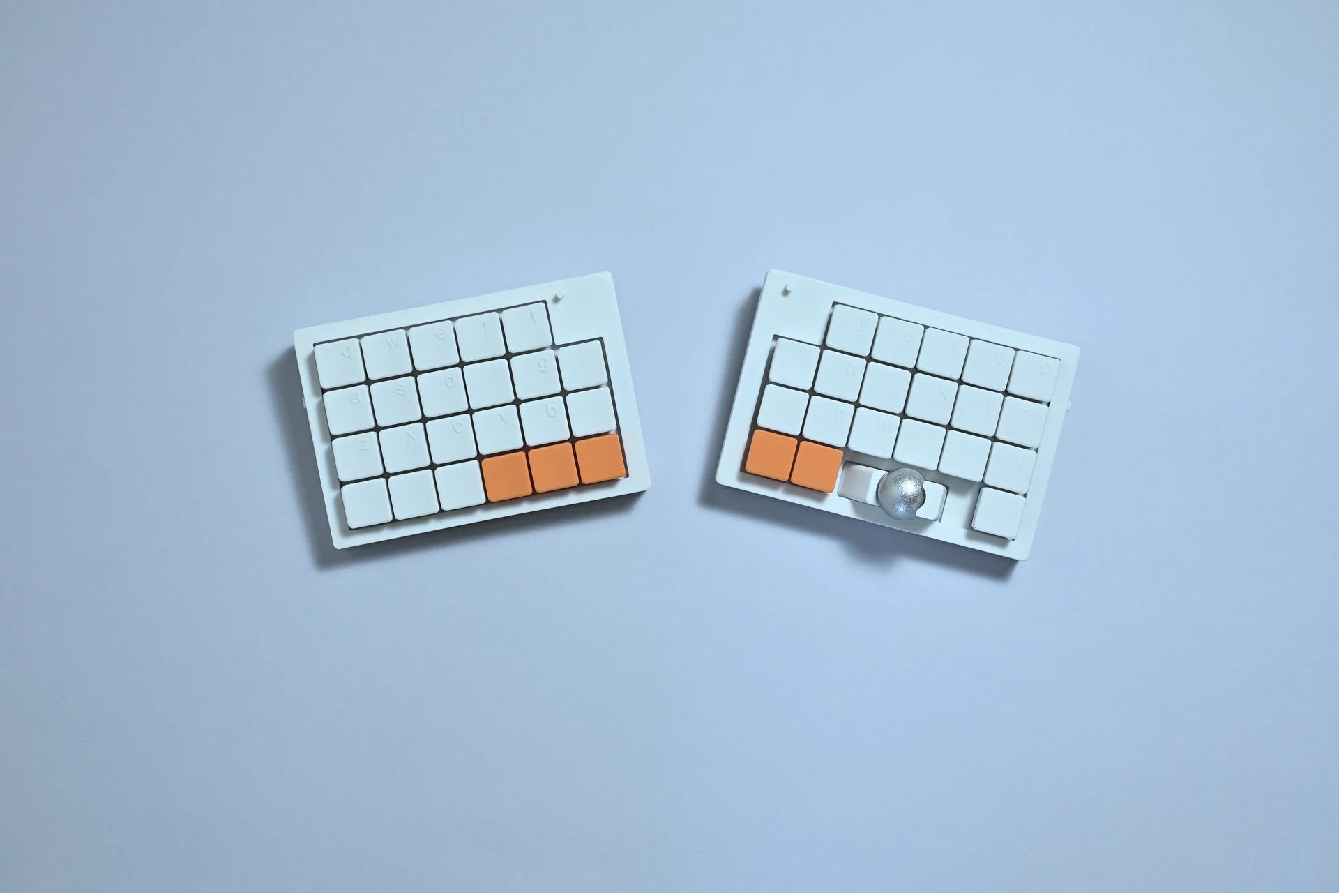 minimal-keysの左右分離型キーボード。白いキー、オレンジの親指キーとトラックボール